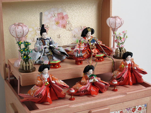 オレンジ女雛とグレー男雛の五人揃いをピンクの宝箱に収めた組み立て簡単のかわいい収納飾りです。