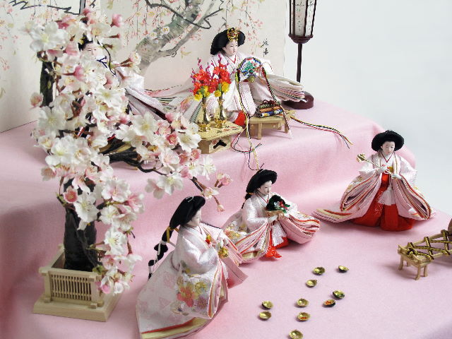 淡い淡いピンクのお雛様を毛氈を敷いた二段飾りにしました。桐箱に収納します。桜の木が美しい創作雛人形です。