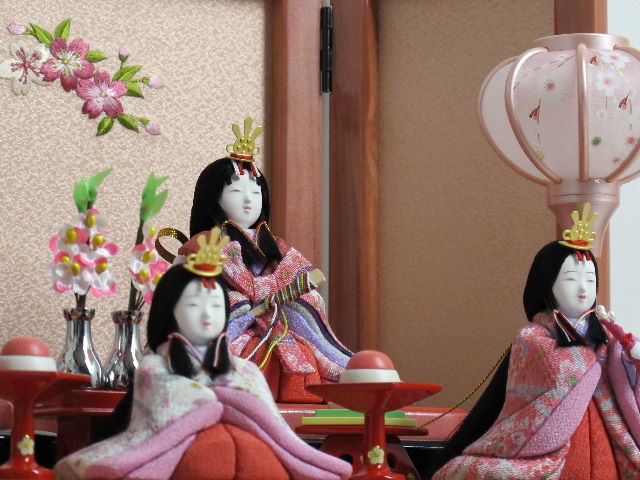 女雛は白とピンク、男雛はブルーの桜花びら柄衣装の木目込み人形五人揃いです。桜の刺繍がポイントのパールローズピンクの収納台に飾りました。