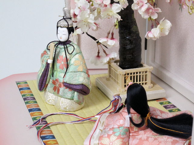 淡い色合いの桜柄衣装の座りと立ちの雅な木目込み人形をかわいいホワイトピンク収納台に桜で飾りました。