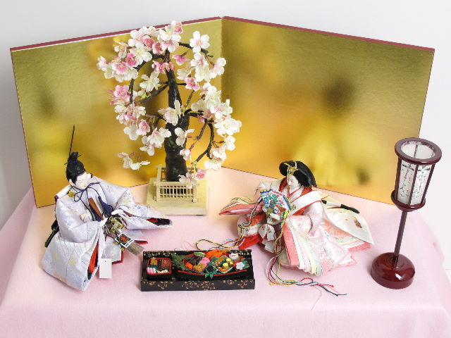 淡い桜色の女雛と藤色の男雛をピンクの毛氈で桐箱の上に金屏風で飾りました。