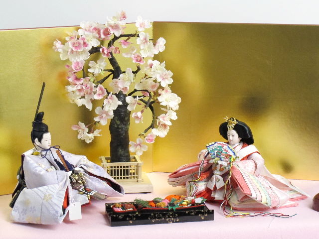 淡い桜色の女雛と藤色の男雛をピンクの毛氈で桐箱の上に金屏風で飾りました。