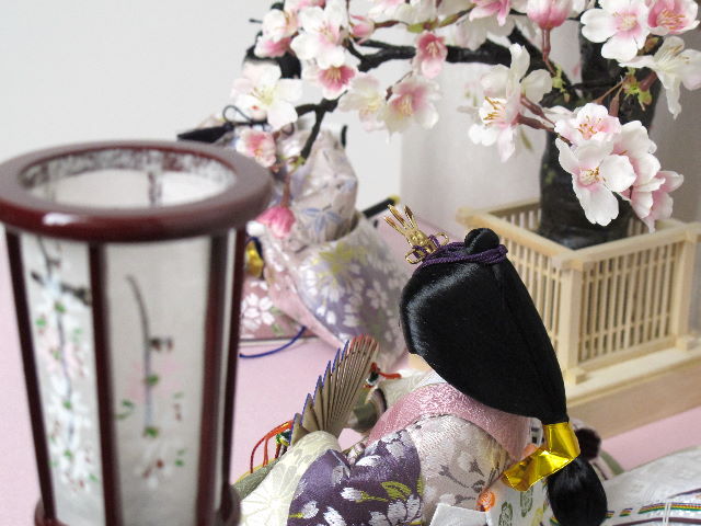 落ち着いた色合いの重ねと桜模様の衣装が特徴のお雛さまを桜屏風の前に大きな桜の木と共に優雅に飾りました。桐箱に収める便利な収納タイプです。