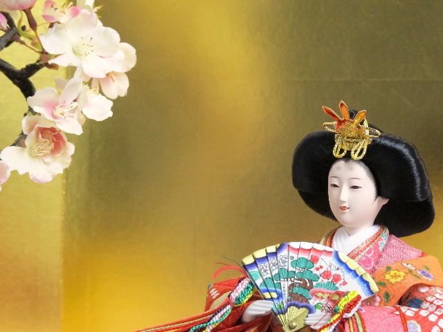 女雛は赤、男雛は黒。かわいい色合いの友禅衣装のお雛さまをピンクの毛氈で桐箱の上に金屏風で飾りました。
