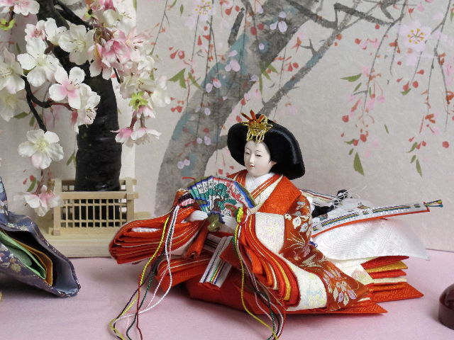 オレンジの女雛と紫の男雛を枝垂桜と桜絵屏風で優雅に飾った桐箱収納式のひな人形です。