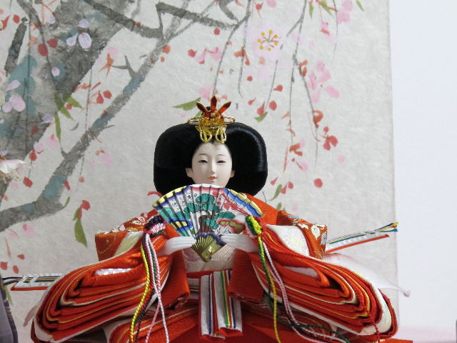 オレンジの女雛と紫の男雛を枝垂桜と桜絵屏風で優雅に飾った桐箱収納式のひな人形です。