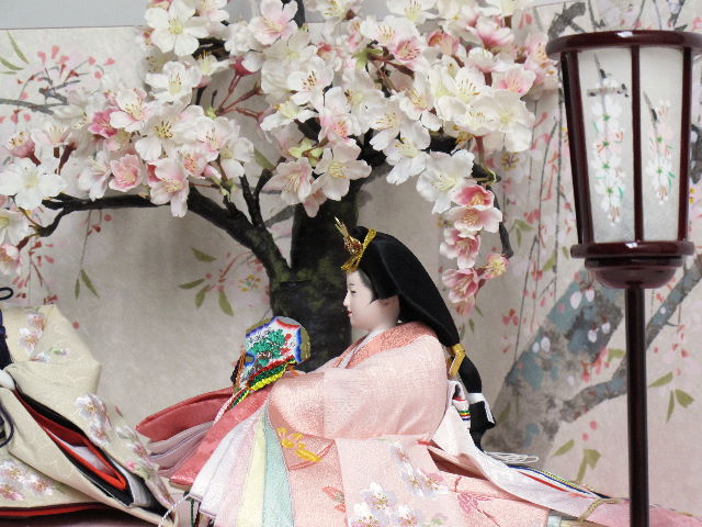 桜色のおひなさまをを桜屏風の前に大きな桜の木と共に優雅に飾りました。桐箱に収める便利な収納タイプです。