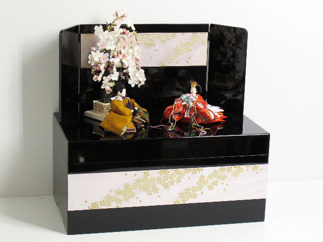 伝統的な黄呂染めのお雛さまを桜吹雪をデザインした黒塗りの収納箱と組み合わせました。