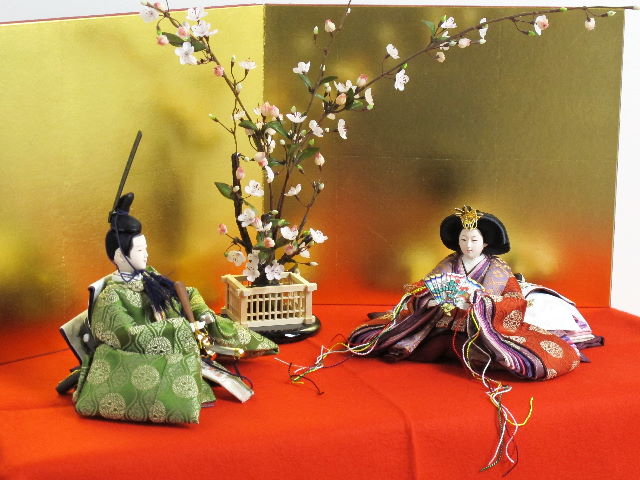 平安貴族の愛用した有職文様、鶴の丸を正絹衣装に織り込み着せ付けた落ち着いたお雛さまを向かい合わせに白梅の木と並べます。