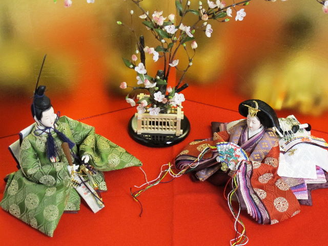 平安貴族の愛用した有職文様、鶴の丸を正絹衣装に織り込み着せ付けた落ち着いたお雛さまを向かい合わせに白梅の木と並べます。