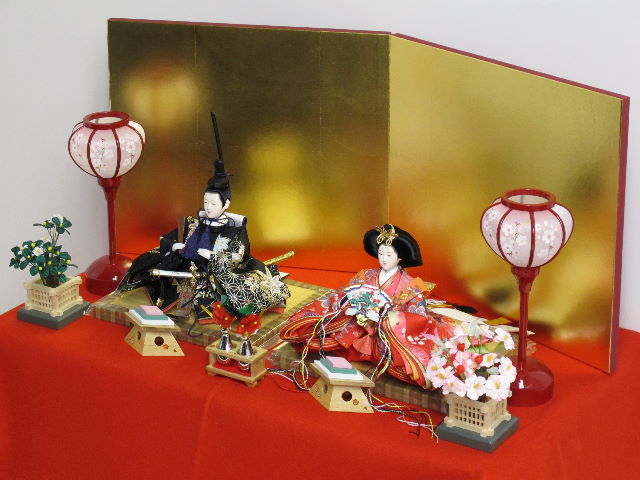 女雛は赤、男雛は黒。かわいい色合いの友禅衣装のお雛さまを金屏風と雪洞、菱三宝でオーソドックスに飾ります。