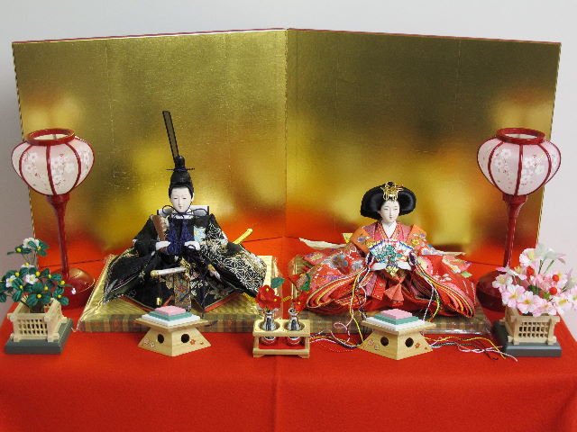 女雛は赤、男雛は黒。かわいい色合いの友禅衣装のお雛さまを金屏風と雪洞、菱三宝でオーソドックスに飾ります。