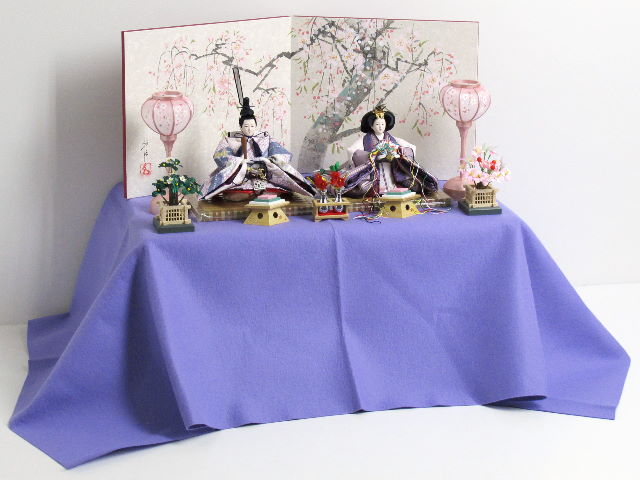 この小ささでも上仕立て。コンパクトでも上質。高貴な紫を重ねや唐衣に用いた雛を手描きの桜屏風と雪洞、菱三宝でオーソドックスに飾ります。