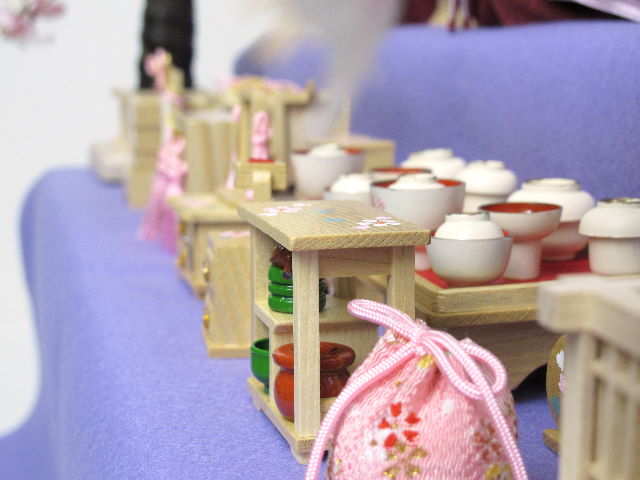 落ち着いた紫グラデーションに桜刺繍のアクセントが入った渋めの雛人形を三段飾りにしました。嫁入り道具がすべて揃った飾りです。オプションで毛氈・屏風がアレンジできます。