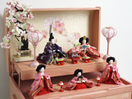 赤の女雛、濃い紫の男雛、ピンクの官女をピンクの宝箱に収めた組み立て簡単のかわいい収納飾りです。