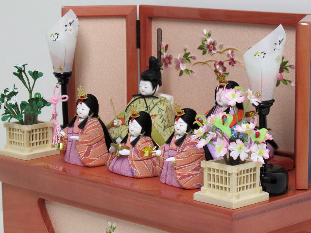 落ち着いた衣装の木目込み人形の五人飾りです。桜柄の刺繍がポイントのピンク色の収納台に飾りました。