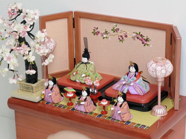 落ち着いた衣装の木目込み人形の五人揃いです。桜の刺繍がポイントのパールローズピンクの収納台に飾りました。