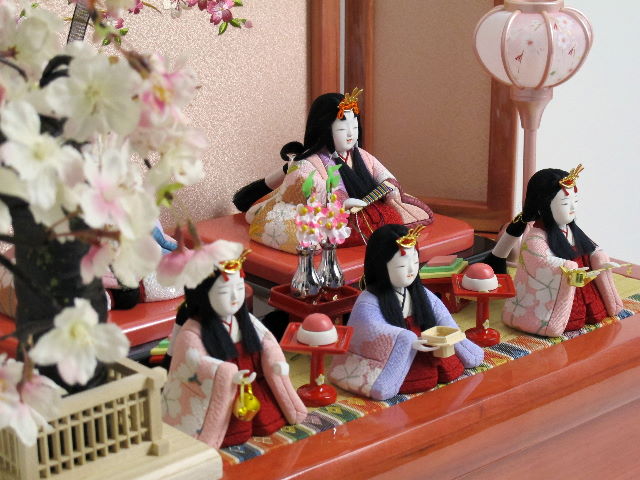 パステルカラーの衣装がかわいい木目込み人形の五人揃いです。桜の刺繍がポイントのパールローズピンクの収納台に飾りました。