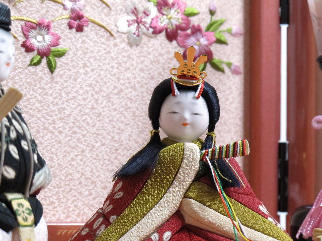 萩模様衣装の木目込み人形です。女雛が座り、男雛が立っています。桜柄の刺繍がポイントのピンク色の収納台に飾りました。