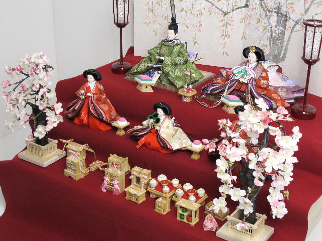 平安貴族の愛用した有職文様、鶴の丸を正絹衣装に織り込み着せ付けた落ち着いたお雛さまと嫁入り道具一式を毛氈三段の上に並べます。オプションで毛氈・屏風がアレンジできます。