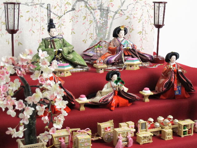 平安貴族の愛用した有職文様、鶴の丸を正絹衣装に織り込み着せ付けた落ち着いたお雛さまと嫁入り道具一式を毛氈三段の上に並べます。オプションで毛氈・屏風がアレンジできます。