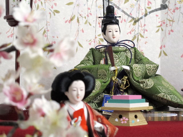 平安貴族の愛用した有職文様、鶴の丸を正絹衣装に織り込み着せ付けた落ち着いたお雛さまと嫁入り道具一式を毛氈三段の上に並べます。オプションで毛氈・屏風がアレンジできます。