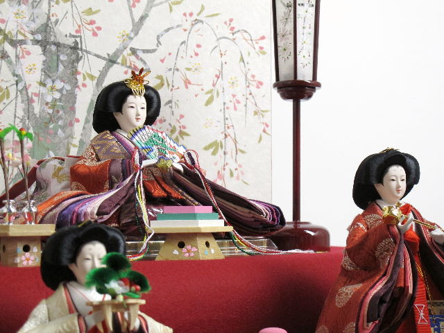 平安貴族の愛用した有職文様、鶴の丸を正絹衣装に織り込み着せ付けた落ち着いたお雛さまと嫁入り道具一式を毛氈三段の上に並べます。オプションで毛氈・屏風がアレンジできます。