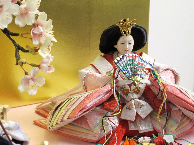 淡い桜色の女雛と藤色の男雛をピンクの毛氈で桐箱の上に金屏風で飾りました。