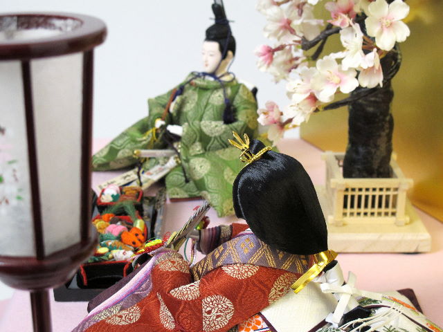 平安貴族の愛用した有職文様、鶴の丸を正絹衣装に織り込み着せ付けた落ち着いたお雛さまをピンクの毛氈で桐箱の上に金屏風で飾りました。