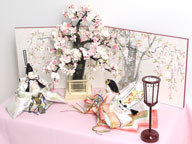 ピンクと白の明るい色合いのお雛様を桜屏風の前に大きな桜の木と共に優雅に飾りました。桐箱に収める便利な収納タイプです。