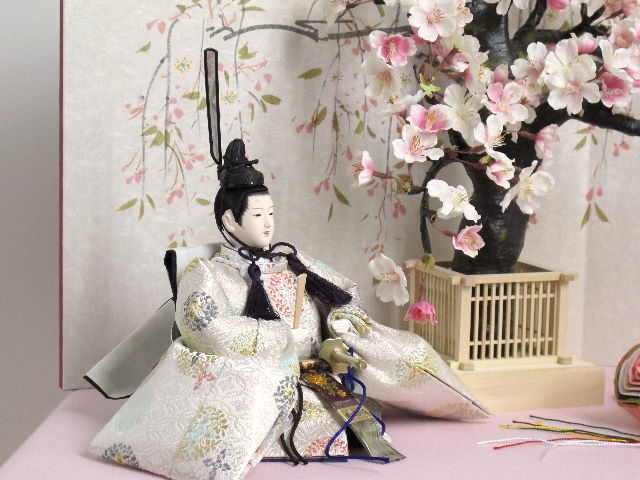 ピンクと白の明るい色合いのお雛様を桜屏風の前に大きな桜の木と共に優雅に飾りました。桐箱に収める便利な収納タイプです。