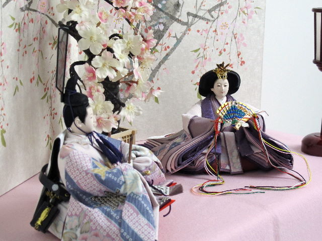 この小ささでも上仕立て。コンパクトでも上質。高貴な紫を重ねや唐衣に用いた雛を枝垂桜と桜絵屏風で優雅に飾った桐箱収納式のひな人形です。