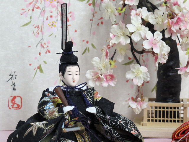 女雛は赤、男雛は黒。かわいい色合いの友禅衣装のお雛さまを枝垂桜と桜絵屏風で優雅に飾った桐箱収納式のひな人形です。