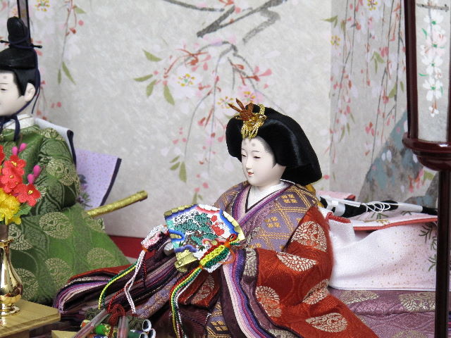 平安貴族の愛用した有職文様、鶴の丸を正絹衣装に織り込み着せ付けた落ち着いたお雛さまを桐箱を台として手描きの桜屏風で飾りました。便利な収納タイプです。