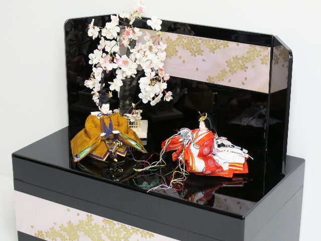 伝統的な黄呂染めのお雛さまを桜吹雪をデザインした黒塗りの収納箱と組み合わせました。