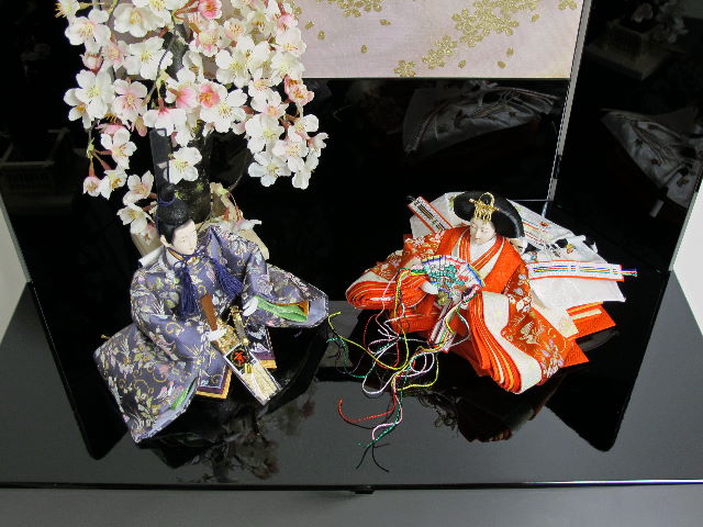 オレンジの女雛と紫の男雛を桜吹雪をデザインした黒塗りの収納箱と組み合わせました。