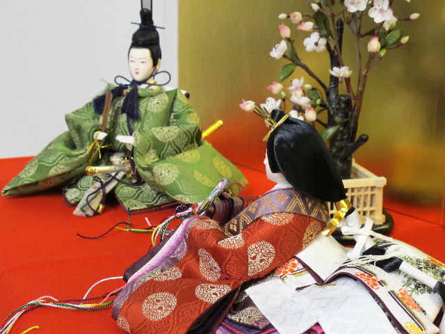 平安貴族の愛用した有職文様、鶴の丸を正絹衣装に織り込み着せ付けた落ち着いたお雛さまを向かい合わせに白梅の木と並べます。