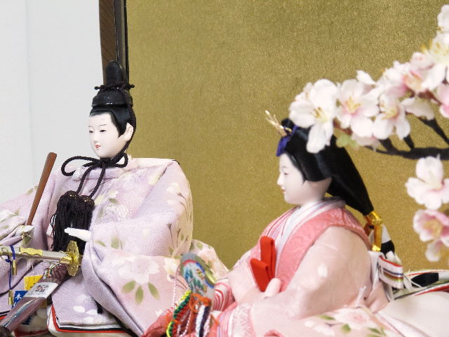 本格的な仕立てと着せ付けが自慢。おとなしいピンクの地に桜をデザインした優しい雰囲気のおひなさまを宮廷風に飾りました。