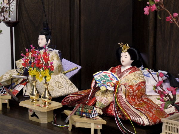 鳳凰が金で織り込まれた豪華な衣装の雛人形を人気の梅飾りにしました。