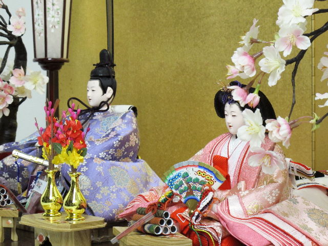 桜模様の明るく清々しい衣装を着せ付けたの仕立て自慢のおひなさまを創作金屏風と巻物前飾り、左右の桜で重厚に飾った雛人形です。