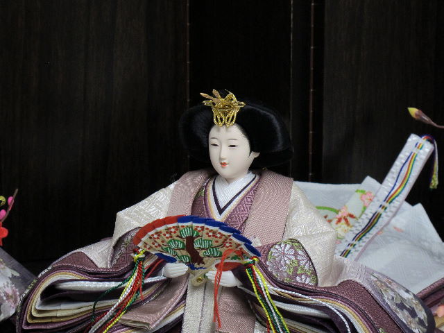 ちょっと渋めの紫のグラデーションと重ね、明るい桜の刺繍がアクセントになった品の良い雛人形を木目茶塗り台・六曲屏風と両脇からの紅白梅で引き立たたせました。