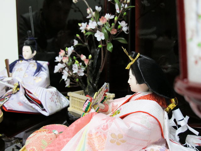 淡い桜色の女雛と藤色の男雛をシンプルに白梅の木と飾りました。重厚な溜塗り台を使用した創作親王です。