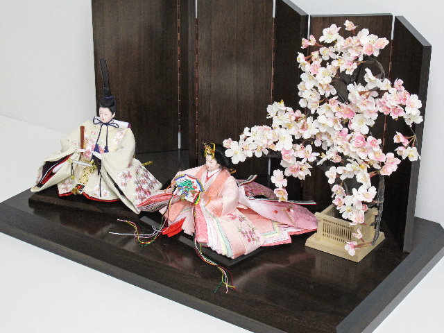 桜色のおひなさまを茶塗り台に置いて、大きな桜の木で引き立てたシンプルな飾りです。